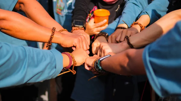 Group of young Asian people making a fist bump gesture in circle as symbol of unity in diversity.