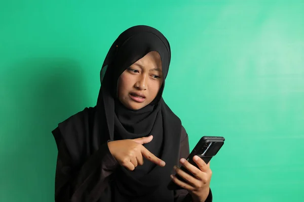 Zszokowany Młoda Azjatka Czarny Hidżab Lub Chusta Wskazując Smartfon Odizolowany — Zdjęcie stockowe