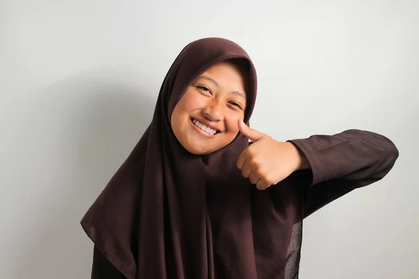 히잡이나 머리쓰개를 아시아 소녀가 바탕에 엄지손가락을 벌리고 — 스톡 사진