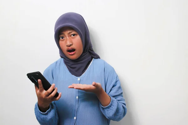 Zdezorientowana Młoda Azjatka Hidżabie Ubrana Luźną Koszulę Trzymająca Telefon Białym — Zdjęcie stockowe