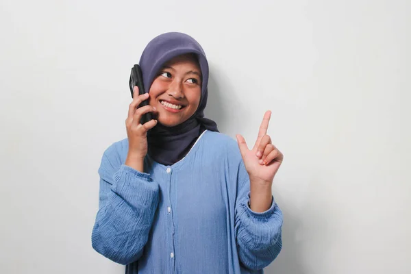 평상복 차림으로 히잡을 아시아 소녀는 배경에 떨어져 공간을 가리키면서 전화를 — 스톡 사진