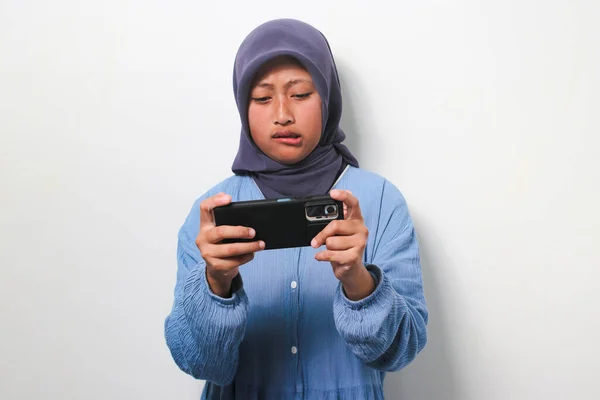차림의 아시아 소녀가 배경에 고립된 전화로 게임을 짜증을 — 스톡 사진