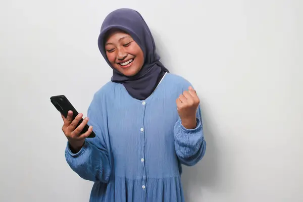 Возбужденная Молодая Азиатка Хиджабе Повседневной Рубашке Глядя Смартфон Получающая Хорошие — стоковое фото