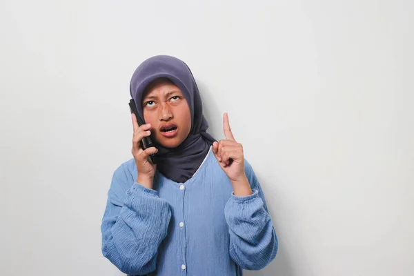 Zdenerwowana Młoda Azjatka Hidżabie Ubrana Luźną Koszulę Trzymająca Telefon Wskazująca — Zdjęcie stockowe