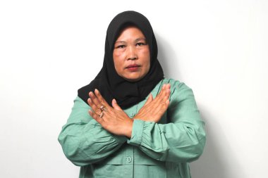 Kızgın Orta yaşlı, siyah tesettürlü, sıradan gömlekli Asyalı kadınlar hayır diyerek kollarını kavuşturdu ve beyaz arka planda izole edilmiş reddedilme hareketi yaptı..