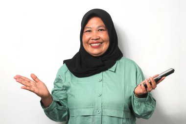 Heyecanlı Orta yaşlı Asyalı kadınlar siyah başörtüsü takıyor ve cep telefonu kullanarak günlük gömlekler giyiyorlar ve başarıyı kutluyorlar, iyi haberleri beyaz arka planda izole ediyorlar..