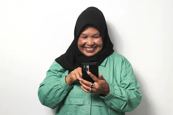 Happy Middle aged Asian women wearing black hijab and dressed in casual shirt using a mobile phone, shopping online, ordering delivery isolated over white background.