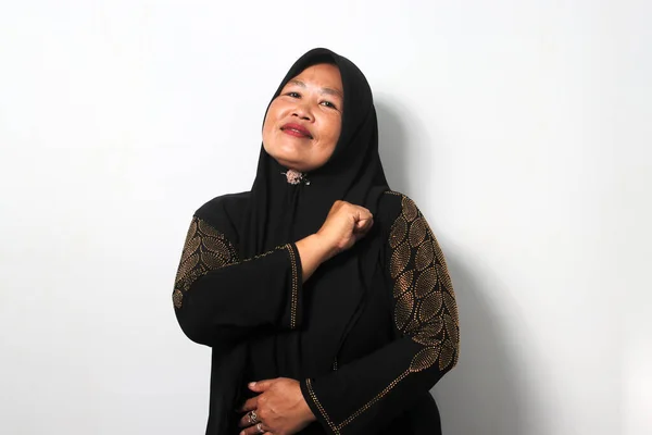 自信を持って中年アジアの女性を身に着けている黒ヒジャーブとカジュアルシャツを示す誇り高いジェスチャーとともに手胸の上に白い背景に孤立 — ストック写真