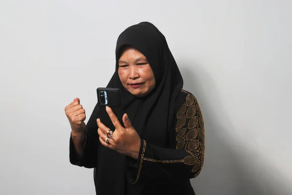 Podekscytowana Azjatka Średnim Wieku Czarnym Hidżabie Abaja Patrząc Telefon Gestem — Zdjęcie stockowe