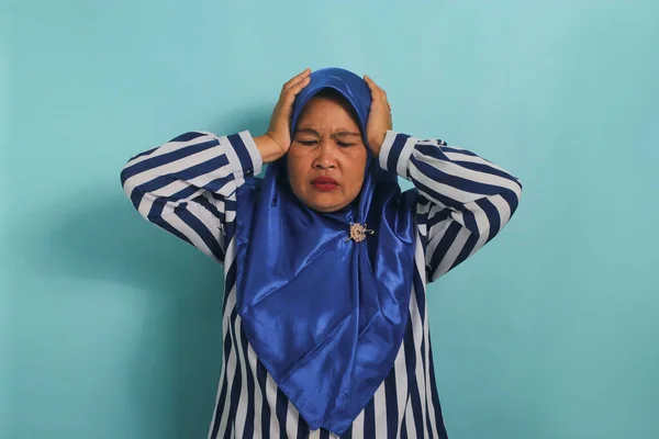 一名身穿蓝色头巾和条纹衬衫的亚洲中年妇女的画像 显示她患有头痛 偏头痛或疾病 站在蓝色背景下 — 图库照片