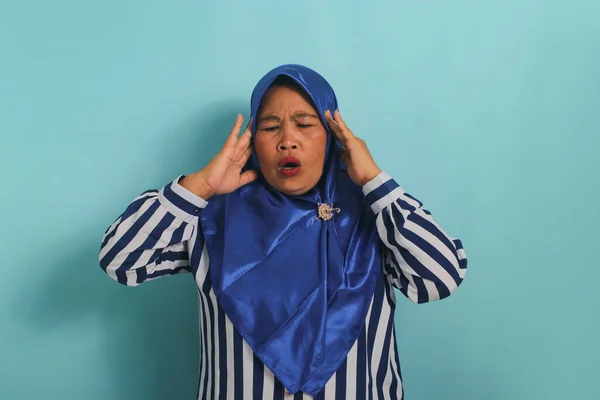 一名身穿蓝色头巾和条纹衬衫的亚洲中年妇女的画像 显示她患有头痛 偏头痛或疾病 站在蓝色背景下 — 图库照片