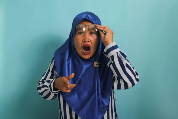 Zdziwiona Azjatka Średnim Wieku Niebieskim Hidżabie Koszuli Paski Wskazuje Palcami — Zdjęcie stockowe