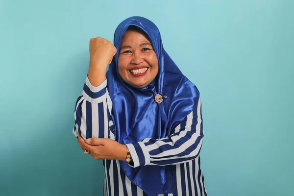 Uśmiechnięta Azjatka Średnim Wieku Niebieskim Hidżabie Koszuli Paski Robi Silny — Zdjęcie stockowe