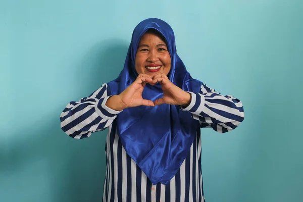 Улыбающаяся Азиатка Средних Лет Синем Хиджабе Полосатой Рубашке Делает Сердечный — стоковое фото