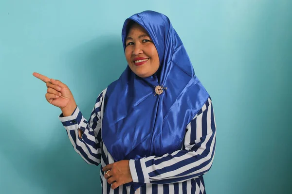 Entuzjastyczna Azjatka Średnim Wieku Niebieskim Hidżabie Pasiastej Koszuli Wskazuje Lewo — Zdjęcie stockowe
