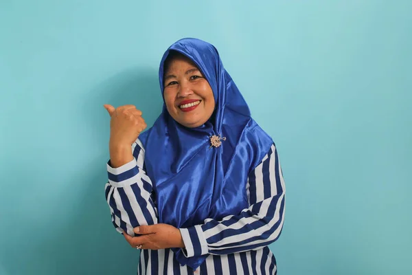 Podekscytowana Azjatka Średnim Wieku Niebieskim Hidżabie Koszuli Paski Wskazuje Lewo — Zdjęcie stockowe