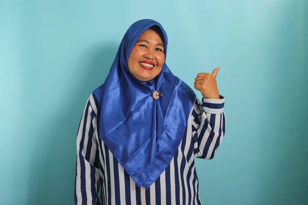 Podekscytowana Azjatka Średnim Wieku Niebieskim Hidżabie Koszuli Paski Wskazuje Lewo — Zdjęcie stockowe
