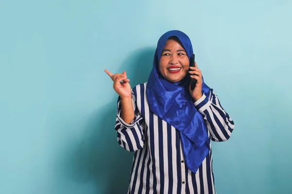 Azjatka Średnim Wieku Niebieskim Hidżabie Pasiastej Koszuli Wskazuje Lewą Przestrzeń — Zdjęcie stockowe