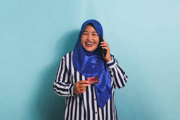 Возбужденная Азиатка Средних Лет Синем Хиджабе Полосатой Рубашке Разговаривает Телефону — стоковое фото