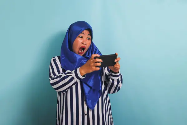 Podekscytowana Azjatka Średnim Wieku Niebieskim Hidżabie Koszuli Paski Grająca Grę — Zdjęcie stockowe