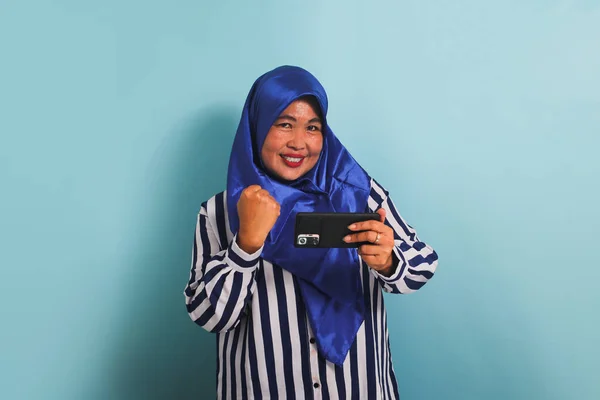 Возбужденная Азиатка Средних Лет Синем Хиджабе Полосатой Рубашке Играющая Игру — стоковое фото