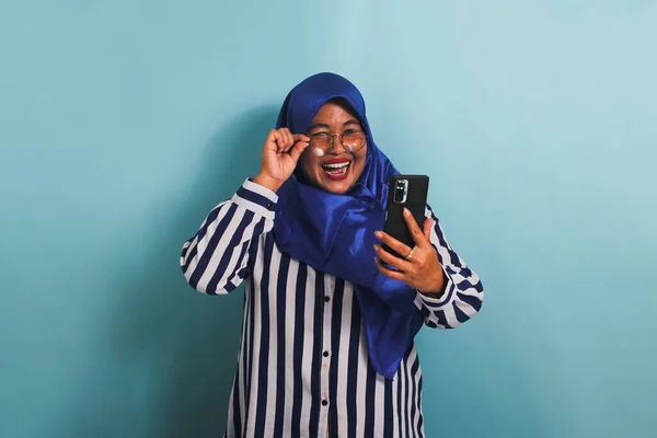 Возбужденная Азиатка Средних Лет Синем Хиджабе Очках Полосатой Рубашке Смеется — стоковое фото