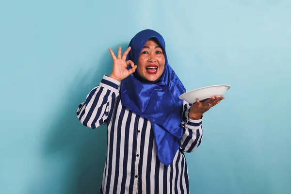 Azjatka Średnim Wieku Niebieskim Hidżabie Koszuli Paski Pokazuje Znak Trzymając — Zdjęcie stockowe