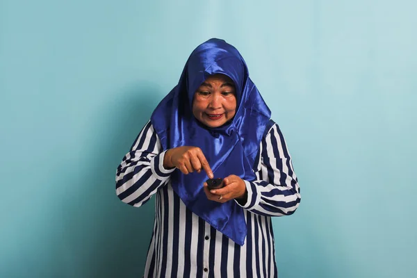 Раздраженная Азиатка Средних Лет Синем Хиджабе Полосатой Рубашке Пытается Переключить — стоковое фото