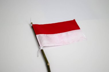 Küçük bir Endonezya bayrağı, beyaz bir arka planda izole edilmiş küçük bir bambu çubuğu üzerinde..