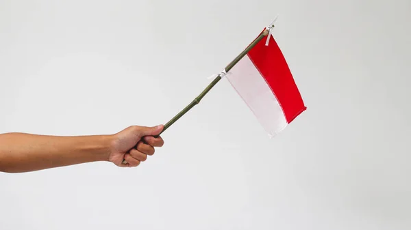 一只手拿着一面小小的印度尼西亚国旗 插在一根竹竿上 用白色的背景隔开 — 图库照片