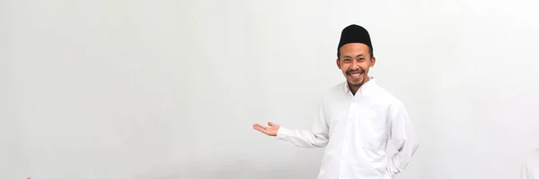 エキサイティングな若いインドネシア人男性は ソングコック ピッチ またはコピアを着て コピスペースの側に手を伸ばし 白い背景で孤立した誰かを招待します — ストック写真