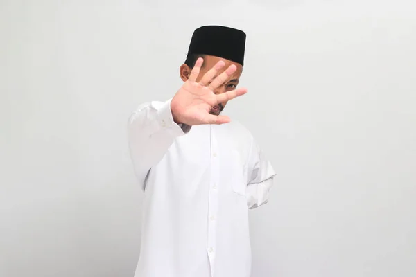すごくひどい ノイズのあるインドネシア人男性は ソングコック ピッチ またはコピアを着用して 白い背景に隔離された嫌悪感のある表現を表示し 何かによって撃退されます — ストック写真