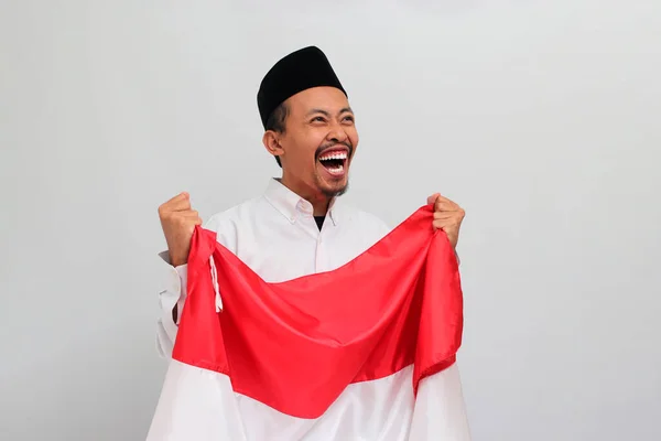 8月17日にインドネシア独立記念日を祝うためにインドネシアの国旗を掲げ 白い背景で孤立した 興奮する若いインドネシア人男性 — ストック写真