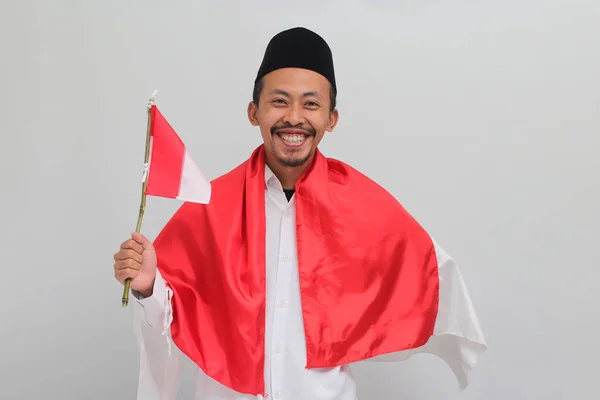8月17日是印度尼西亚独立日 身穿红衣 山核桃或Kopiah的年轻男子兴奋地拿起小旗庆祝印度尼西亚独立日 — 图库照片
