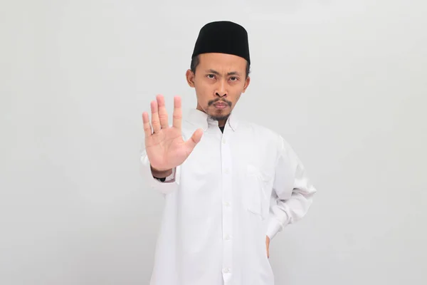 真剣な若いインドネシア人男性は ソングコック ピッチ またはコピアを着て 白い背景で孤立した または禁止することを示す警告のジェスチャーを示しています — ストック写真