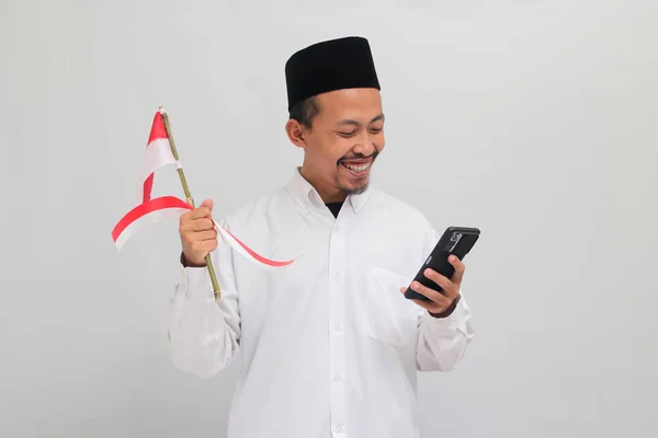 8月17日にインドネシア独立記念日を祝い 白い背景に隔離されたインドネシアの国旗と携帯電話を保持している — ストック写真