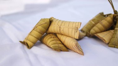Beyaz arka planda bir grup lepet ketan. Lepet ketan geleneksel Endonezya usulü pirinç keki. Glutinous pilavı, rendelenmiş hindistan cevizi, fıstık karışımı ve hindistan cevizi yapraklarına sarılmış..