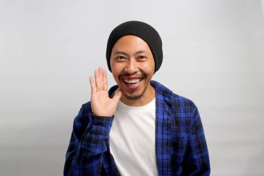 Şapka ve günlük gömlek giymiş Asyalı bir adam elini ağzının yanına getiriyor. Sanki bir sırrı paylaşıyormuş gibi. Fısıldıyor ve haylaz bir sohbete girişiyor.