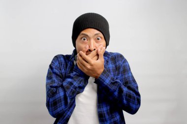 Şapka ve gündelik gömlek giyen ürkmüş genç Asyalı adam kameraya bakar ağzı şaşkınlıkla kaplıdır. Beklenmedik bir söylenti, sır ya da duyuruya tepki verir gibi görünür.