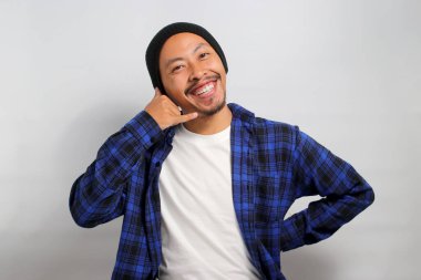 Bereli ve rahat gömlekli çekici Asyalı genç adam beyaz bir arka planda dururken bir 