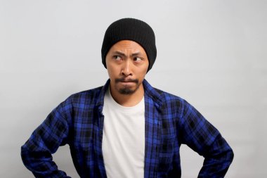 Kafası karışmış genç Asyalı adam dudaklarını büzülüyor ya da çimdikliyor, şüphe ve belirsizlik gösterirken önemli bilgileri paylaşmaktan kaçınıyor. Tereddütlü görünüyor, fotokopi uzayına yan yan bakıyor.