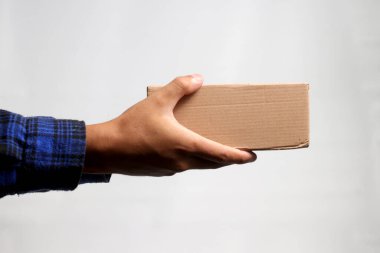 Gri bir arkaplana karşı karton kutu tutan bir el, nakliye, teslimat ve lojistik hizmetleri kavramını gösteren