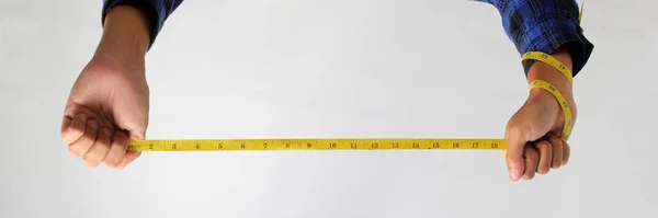 Hand holding a measuring tape against a white background