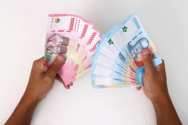 Beyaz arka planda izole edilmiş büyük miktarda Endonezya Rupiah banknotları tutuyor. Yatırım, tasarruf, bağış, kredi ve finansal kavramlar için ideal