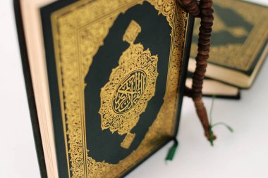 Kuran 'ın anlamı Arapça olan kutsal Kur' an ve beyaz bir zemin üzerine izole edilmiş bir tasbih.