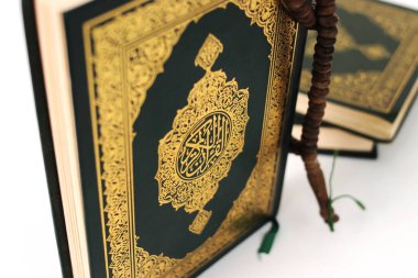 Kuran 'ın anlamı Arapça olan kutsal Kur' an ve beyaz bir zemin üzerine izole edilmiş bir tasbih.