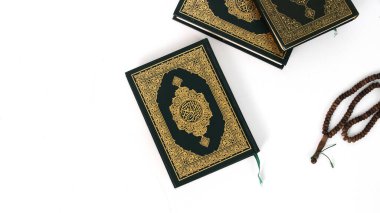 Kuran 'ın anlamı Arapça olan kutsal Kur' an ve beyaz bir zemin üzerine izole edilmiş bir tasbih.