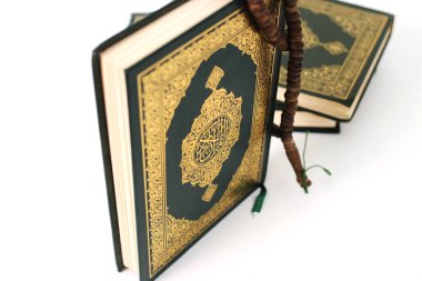 Kuran 'ın anlamı Arapça olan kutsal Kur' an ve beyaz bir zemin üzerine izole edilmiş bir tasbih.