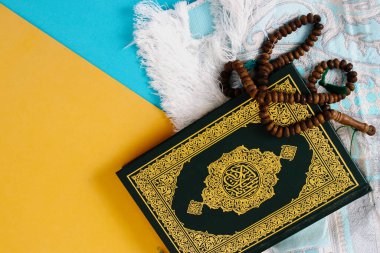Kutsal Kur 'an' da mavi ve sarı arka planda bir paspas ve tasbih var.