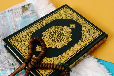 Kutsal Kur 'an' da mavi ve sarı arka planda bir paspas ve tasbih var.